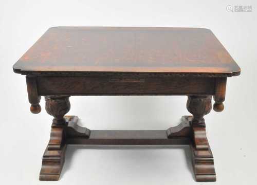 A heavy oak draw-leaf dining table, with rounded corners and carved borders, raised on a heavy