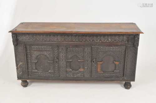 A 17th centuy and later oak coffer, the panelled top over a pair of arched panelled doors, raised on