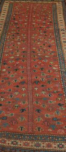 An Eastern woven wool rug, the red field decorated with central foliate motifs, within concentric