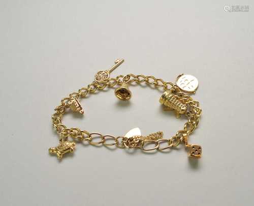 A yellow metal curb link bracelet with attached charms