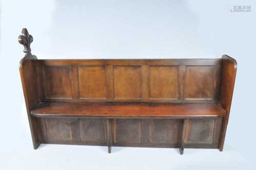 A 19th century and later panelled oak church or hall pew, one end carved with a large fleur-de-lis