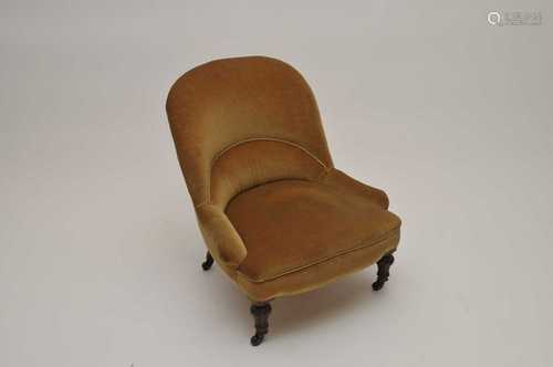 A small, low Victorian upholstered armchair, covered in a gold draylon.