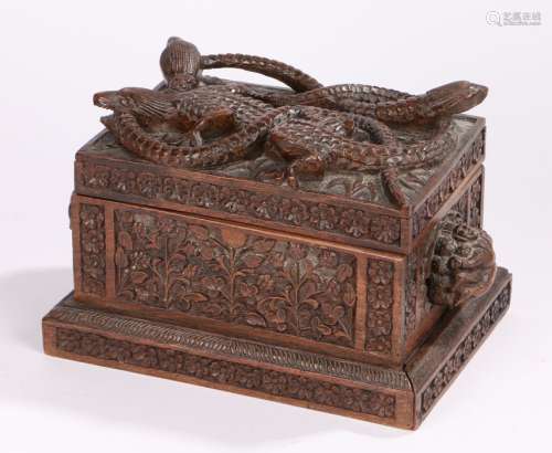 Eastern carved box, with a beast biting a serpent's tail above figural carved handles and foliate
