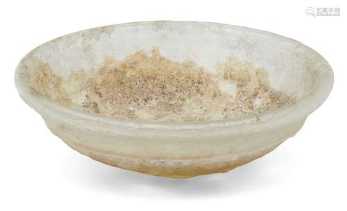 A Roman clear glass dish and a lid, 2nd-4th century AD, the first of deep form with heavy