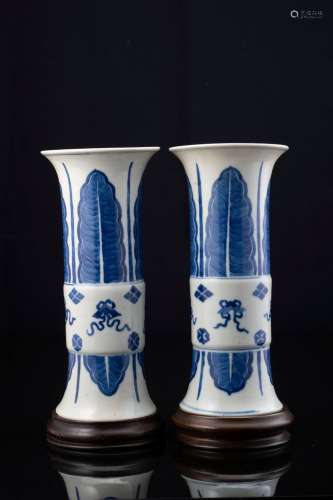 A pair of blue and white porcelain Gu vases, decorated with leaves and auspicious symbols, with wood bases (defects) China, Republic period (1912-1949) Provenance Milanese private collection Gianni Russo Antiquities (h. 26.5 cm.)...