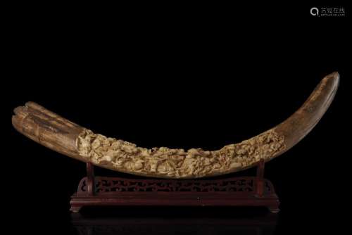 A large ivory fossil tusk, finely carved with the eighteen Luohan among dragons, elephants and various animals, wood base (defects) China, late Qing dynasty (1644-1911) (lungh. 116 cm.) This lot may be subject to Import/Export restriction...