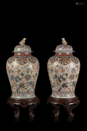 A large pair of Imari jars and covers, pho dogs handles, defects and restorations to one cover, on later wood stands Japan, 19th century (h. 85 cm.)...