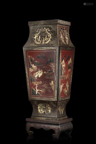 A large square shape lacquered vase decorated with geometric patterns to the neck, and with landscapes on red background to the body, wood lacquered base (slight defects) China, 19th century (h. 108 cm.)...