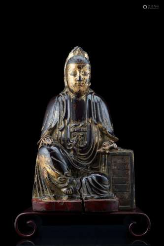 A seated lacquered and parcel gilt wood figure of a Bodhisattva holding a scroll, on a later wood base (defects) China, 17th century Provenance Milanese private collection Gianni Russo Antiquities (h. 40 cm.)...