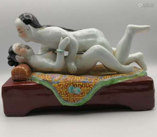 CHINE, circa 1960. Scène érotique en porcelaine émaillée polychrome. Le couple en mouvement est allongé sur un lit dont la couverture déborde de chaque côté. H. 15,5 cm, L. 22 cm, P. 12 cm.
