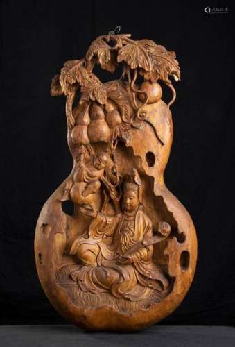 A WOOD GOURD SHAPED PANEL WITH GUANYIN AND A CHILD…