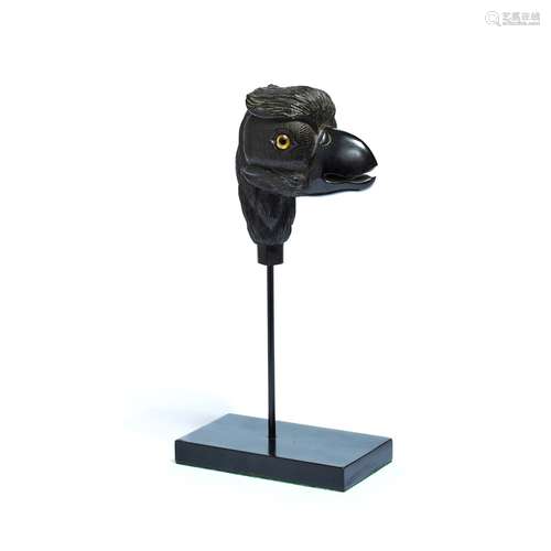 An ebonised and glass inset carved wood model of the head of a bird of prey