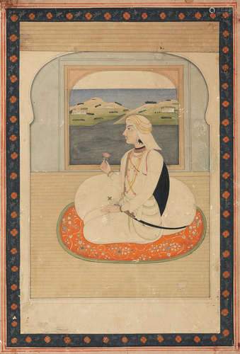 Raja Anidrudh Singh, son of Sansar Chand of Kangra, dressed in Sikh attire, seated holding a flower at a balcony window, a river and hills beyond Kangra, circa 1815-20