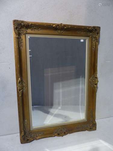 A large rectangular mirror in gilded stucco.