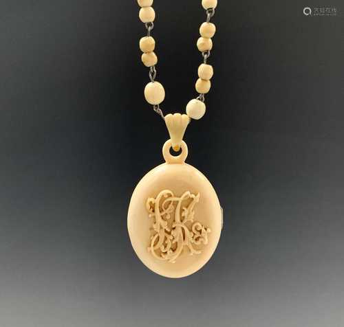 A Chinese ivory canton locket and chain, early 20th century, the monogrammed oval cover opening to