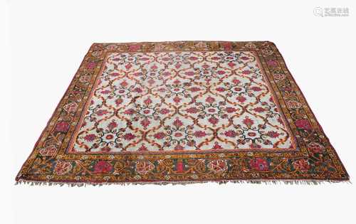 An Indian carpet, the ivory field with all over trellis design enclosing palmettes, within a