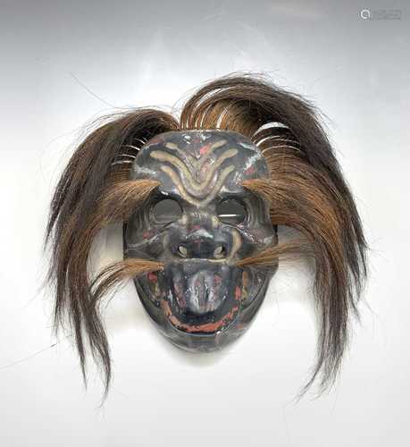 A Japanese carved wooden painted mask, Meiji Period, highlighted with red & gold and with