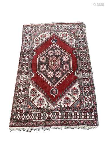 A South West Persian rug, the madder field with a charcoal hooked lozenge medallion, with