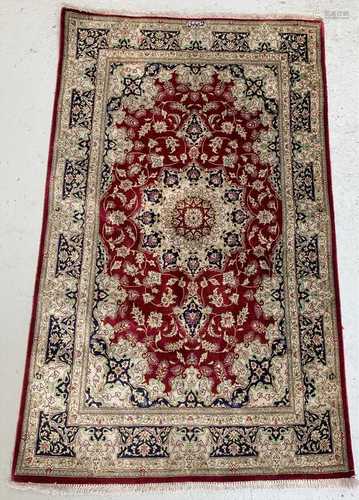 A Qum silk rug, Central Persia, with cartouche to one end enclosing an Islamic inscription, the