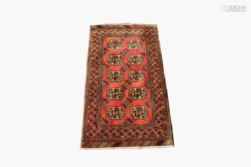 An Afghan rug, the madder field with five rows of two octagonal medallions and hooked guls, within