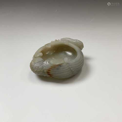 A Chinese carved jade brush pot, 18th century, in the form of a crane grasping a leafy peach branch,