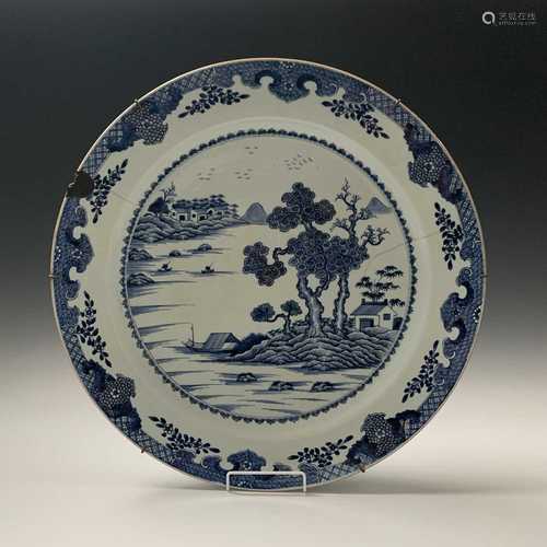 A large Chinese blue and white porcelain charger, 18th century, depicting a riverside scene,