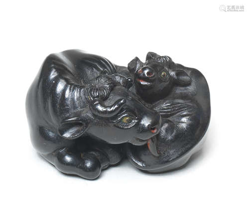 An ebony netsuke of a recumbent ox and young By Tanaka Minko (1735-1816), Tsu, Ise Province, late 18th/early 19th century