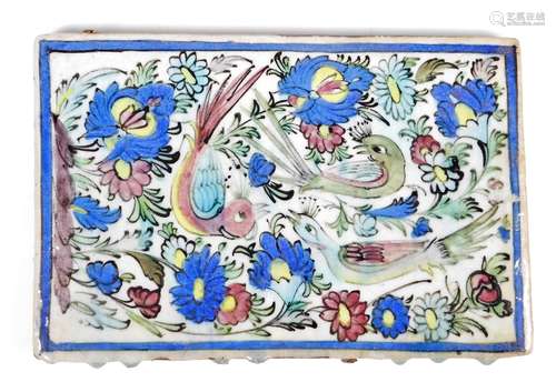 A large 18thC style Persian tile, of oblong form, profusely decorated with flowers and birds,