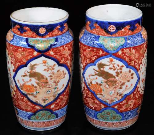 A pair of Imari porcelain vases, each of shouldered cylindrical form decorated with panels of shishi