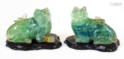 A pair of carved green quartz type figures of temple lions, on wooden plinth bases, 8cm high.