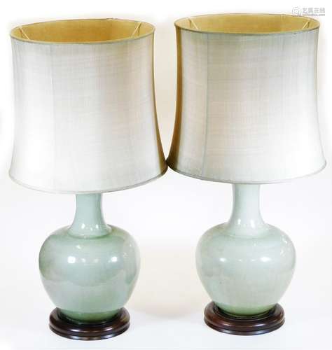 A pair of Chinese celadon porcelain lamp vases, each of bellied circular form with wooden plinths