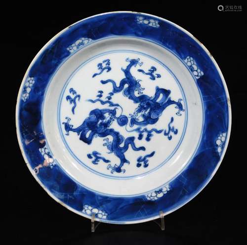 A Chinese circular porcelain dish, decorated with dragons chasing the flaming pearl, within a prunus