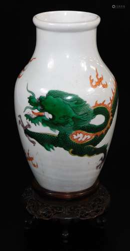 A Chinese porcelain vase, decorated with an enamel dragon, on a heavily carved wooden base, 28cm