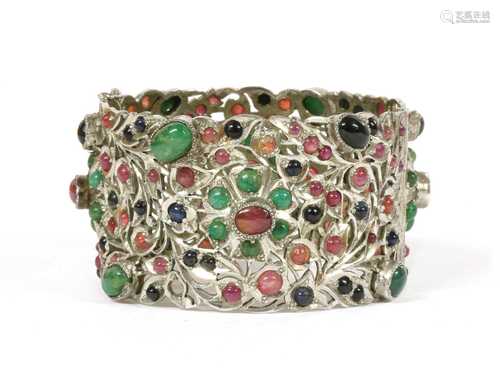 A silver hinged emerald, ruby and sapphire set bangle,