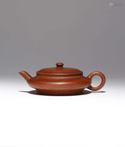 A CHINESE YIXING TEAPOT AND COVER QING DYNASTY The compressed circular body with raised lips