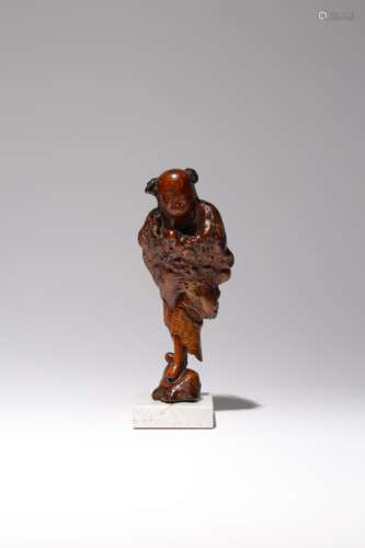 A CHINESE BURR WOOD FIGURE OF A BOY LATE QING DYNASTY Carved standing on a rock with his arms