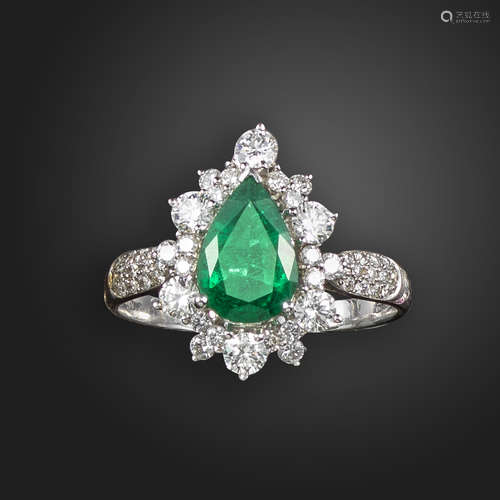 An emerald and diamond cluster ring, set with a pear-shaped emerald within a surround of graduated