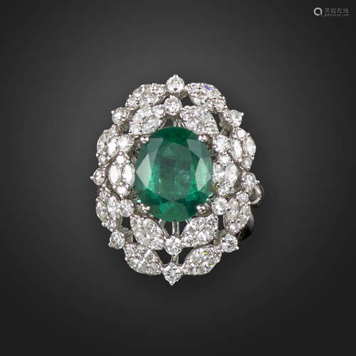 An emerald and diamond cluster ring, the oval-shaped emerald is set within clusters of marquise