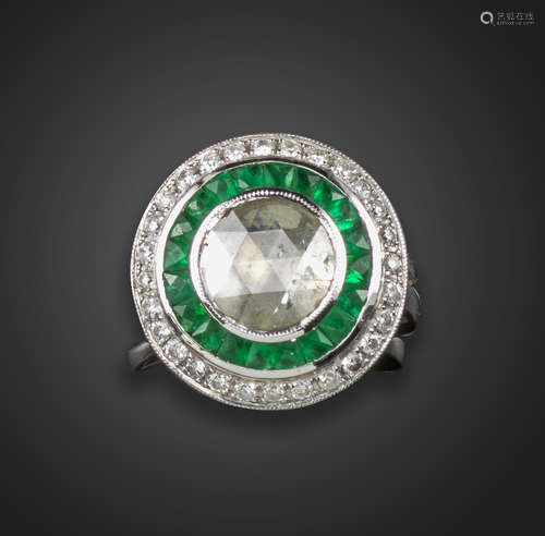 An emerald and diamond target ring, the central rose-cut diamond is set within a surround of