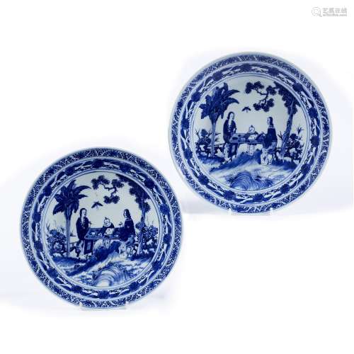 Two blue and white chargers Chinese, 19th Century depicting figures in a garden sat at a table, with