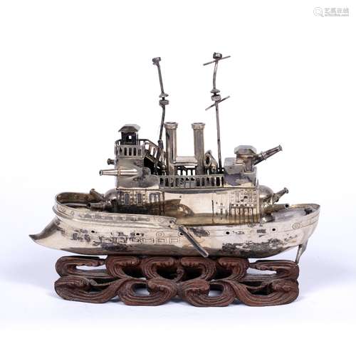 Small white metal model a steam battleship Chinese with various gun turrets, on a wave type carved