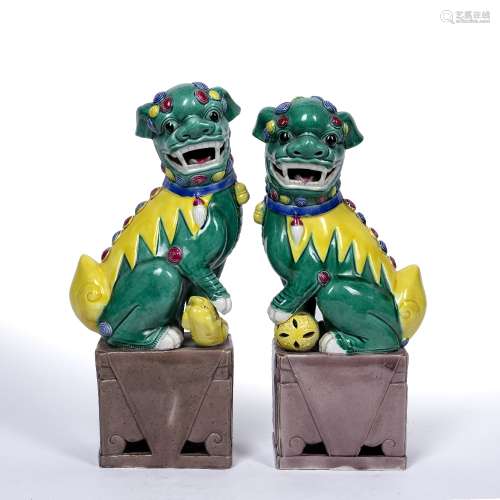 Pair of temple dogs Chinese, 20th Century each with a raised paw resting on an item, with