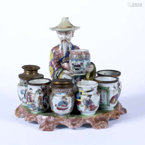 Porcelain model of a merchant French modelled holding a barrel with six further barrels in front,