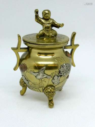 Small gilt bronze tripod covered pot with flower decoration. The grip of the lid showing a seated child. Ht : 14cm