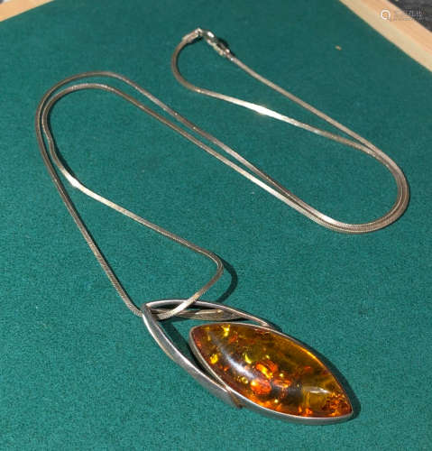AN AMBER PENDANT WITH SILVER CHAIN