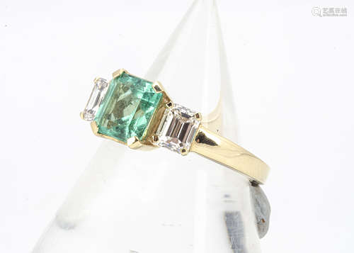 A three stone emerald and diamond 18ct gold dress ring, claw set square cut flanked by two