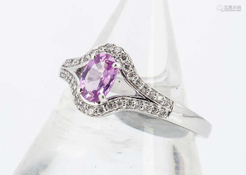 A pink sapphire and diamond dress ring, the oval mixed cut in white 18ct gold with diamond set bezel