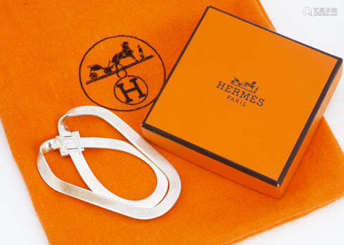 A white metal Hermes money clip, of bow design, marked Hermes, 6cm x 4cm in brown velvet case,