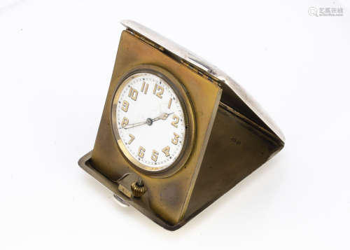 An Art Deco period silver travel clock, the manual wind dashboard style clock in folding case,