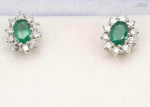 A pair of emerald and diamond cluster ear studs, the oval mixed cut emeralds surrounded by brilliant